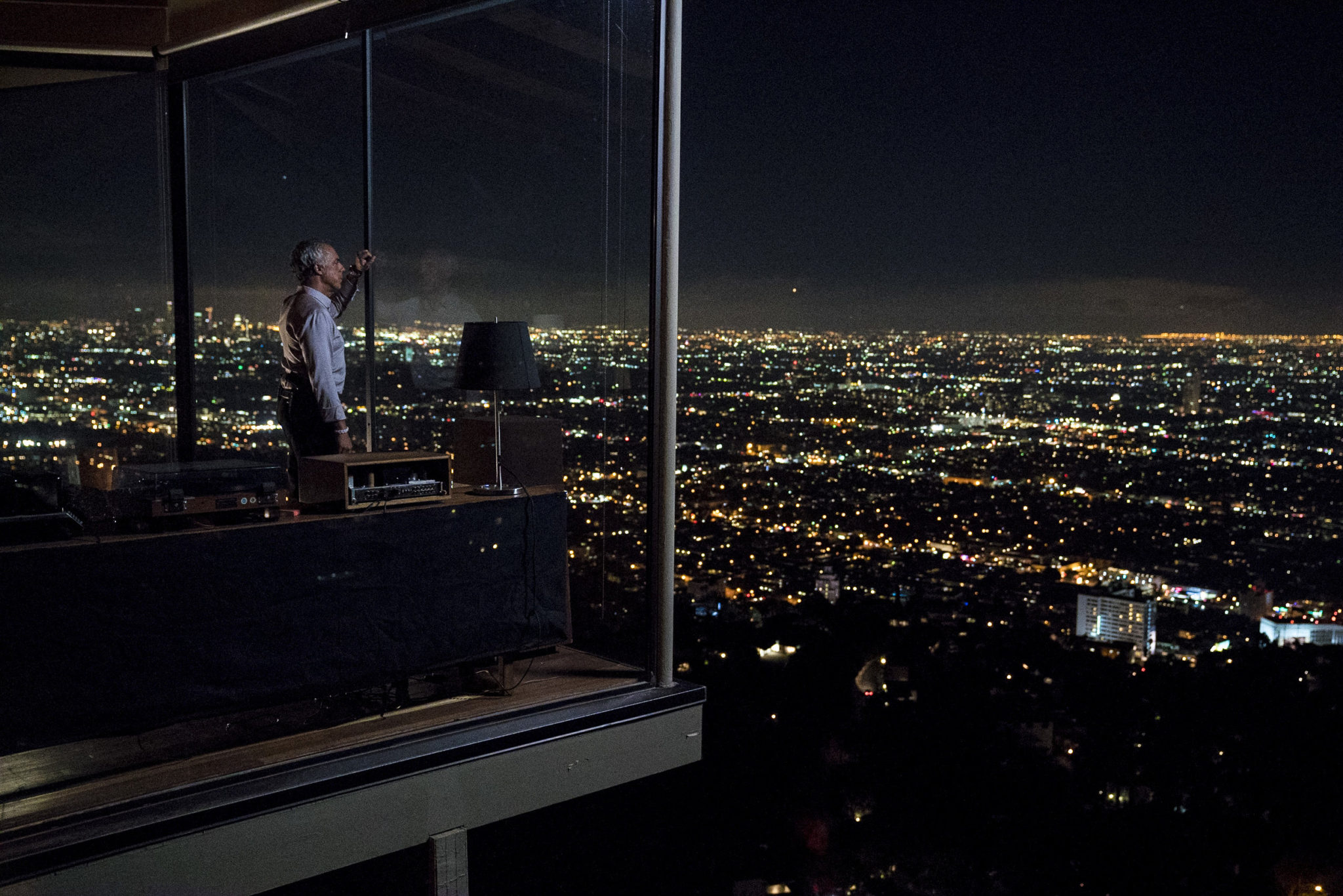 a still of Detective Bosch looking at the city of LA through the all-glass side of his house on the hill